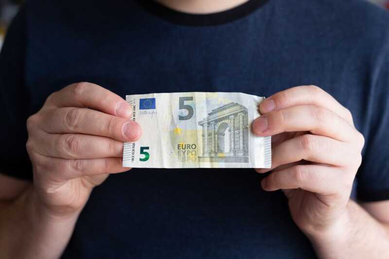 Un billet de 5 euros en main