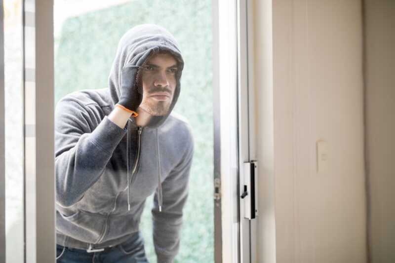 Un cambrioleur s'apprête à rentrer par effraction dans une maison