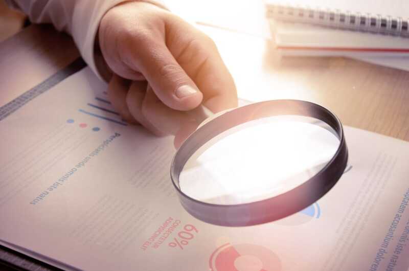 Une personne examine un rapport financier à la loupe