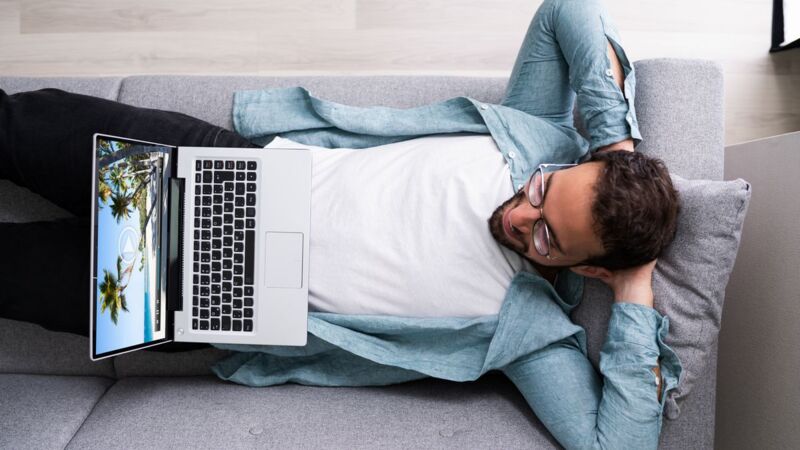 Un homme regarde un film en Wi-Fi sur son ordinateur portable installé dans le canapé