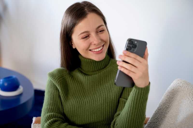 femme regarde l'application de sa sonnette connectée arlo